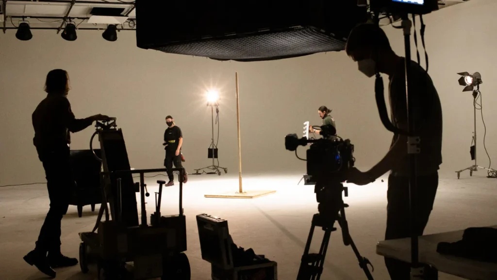 Film crew setting up cameras, lights, and equipment on a professional set, illustrating key production costs in a film budget template such as crew wages, equipment rental, set design, and catering.